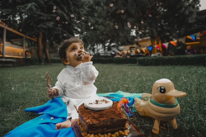 Baby reaching into the cake at the end of an outdoor cake smash