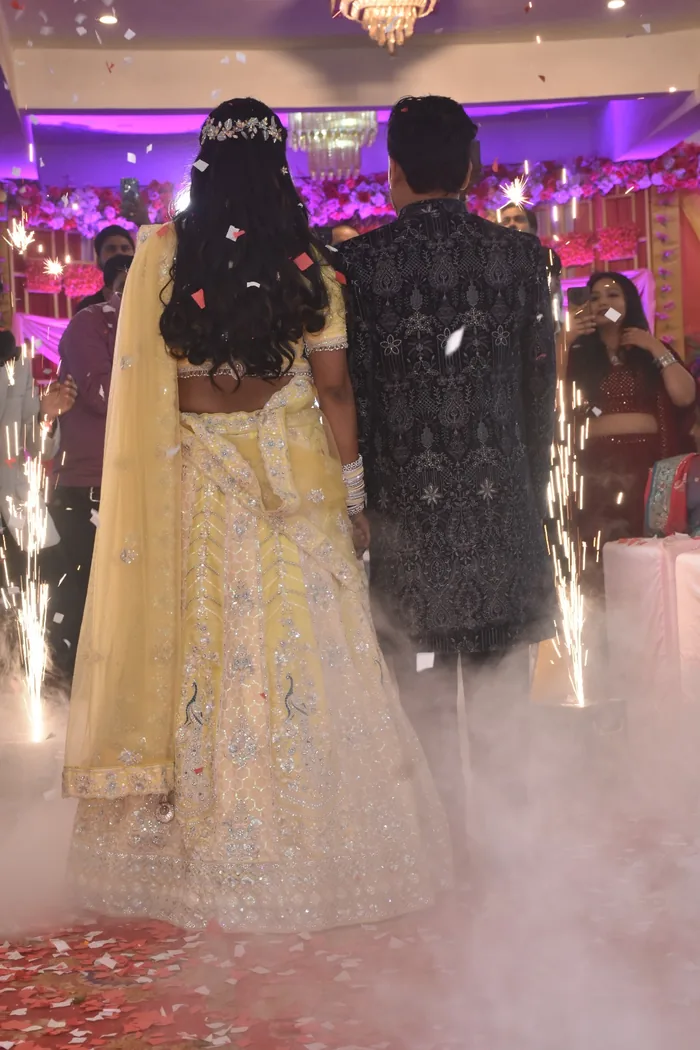 Couple walking into their reception between cold sparklers