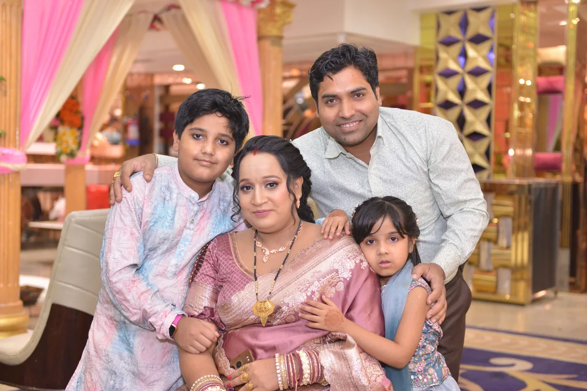 A family photographed together at a ceremony, the hall decorated behind them