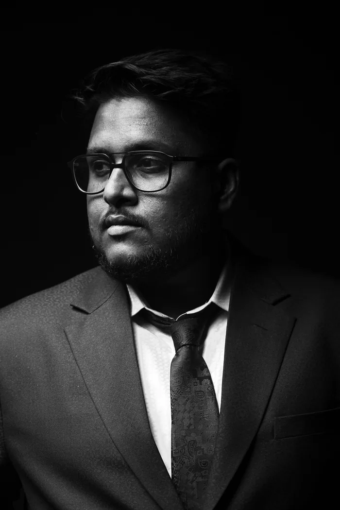 Headshot lit against a dark background in black and white