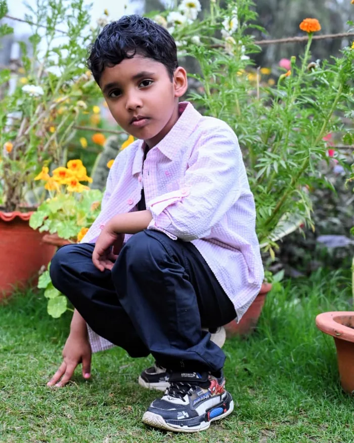 Young boy crouching beside the marigold pots in the garden