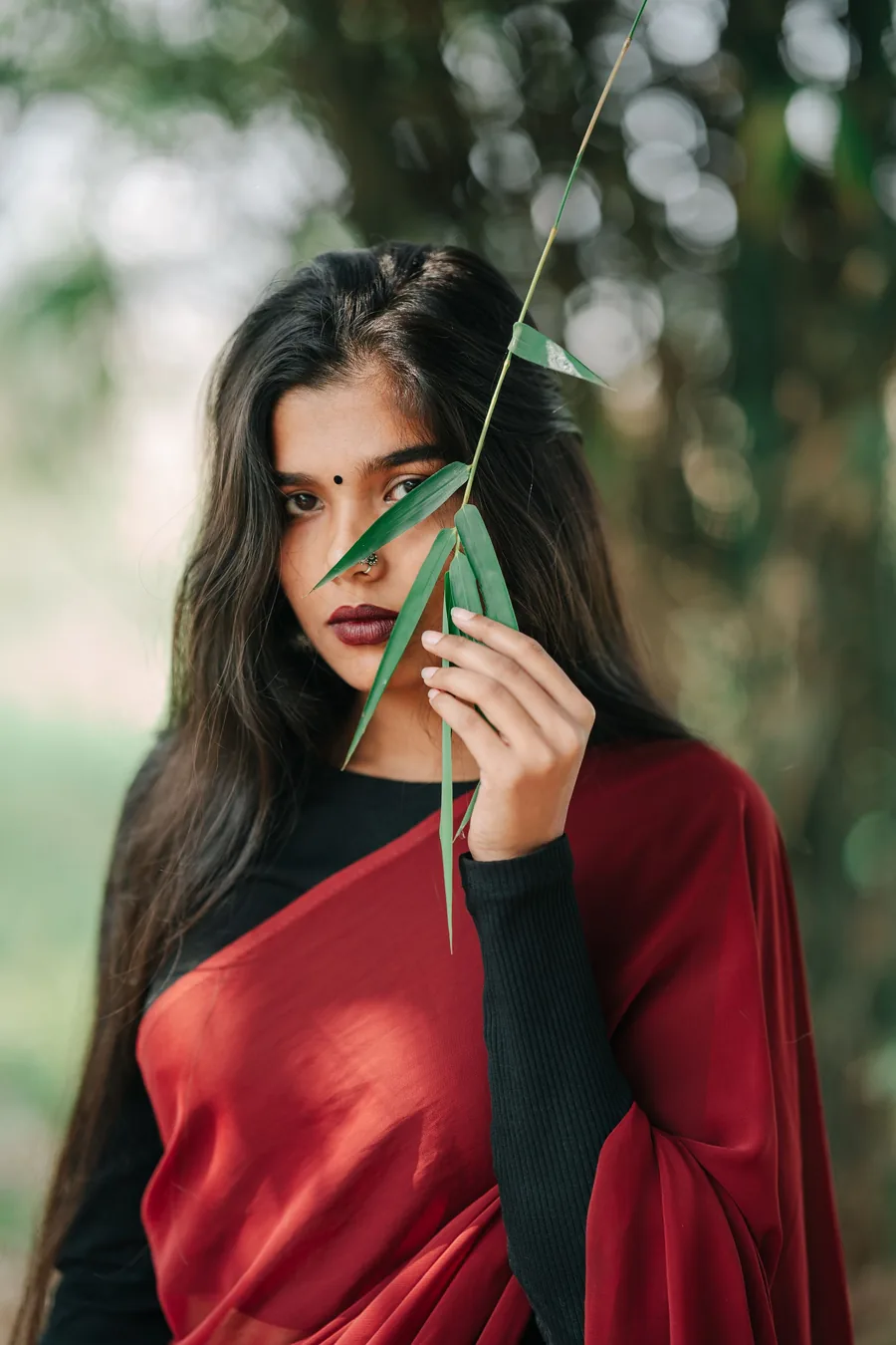 Matrimonial portrait of a woman in a red saree photographed outdoors