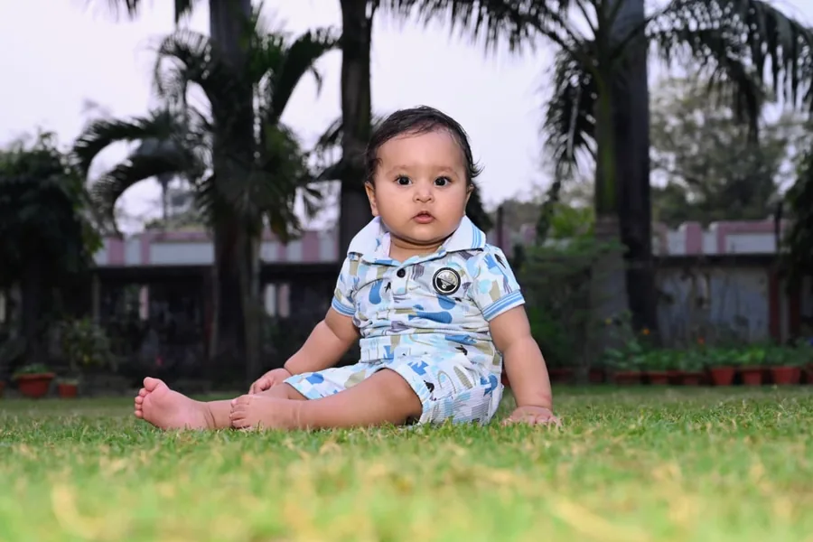Baby sitting up on the grass during an outdoor milestone session