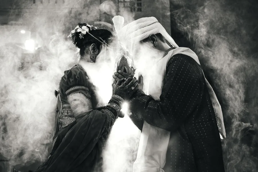 Couple at a ritual with smoke drifting through the frame, in black and white